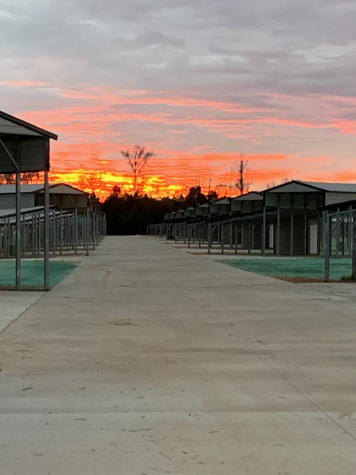 Vivid sunset at the end of the main drive between covered RV sites