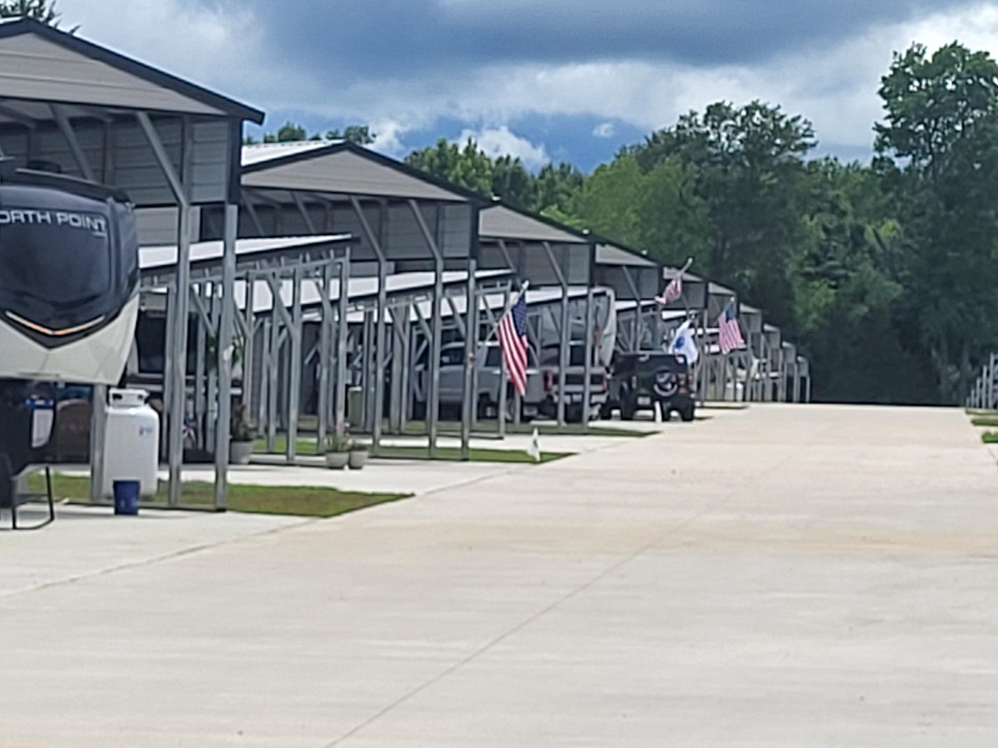 Occupied covered RV sites along a wide concrete park drive